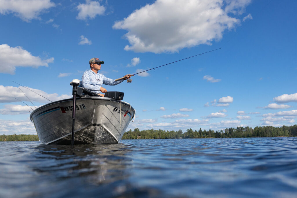 Man fishing on a beautiful lake during a sunny day.