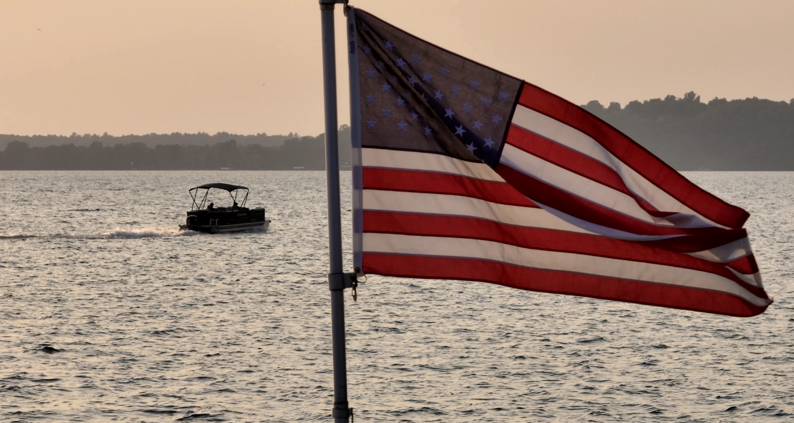 Boat cruising around Gull Lake behind an American flag